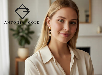 Femeie purtând cercei Antonia Gold tip verigă din aur galben cu pandantiv în formă de cheia sol, design elegant.