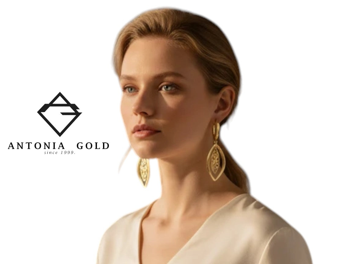 Cercei Antonia Gold din aur galben în formă de frunză filigranată purtați de o femeie într-un decor interior elegant