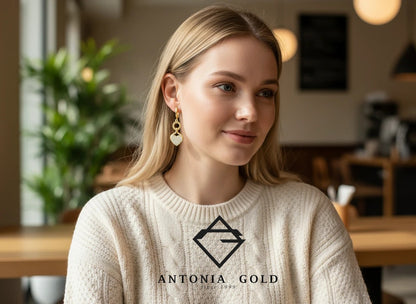 Femeie blondă purtând cercei Antonia Gold tip verigă din aur cu pandantiv în formă de inimă decorat cu pietre strălucitoare