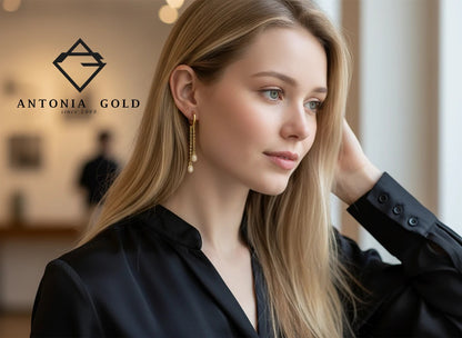 Cercei Antonia Gold din aur cu lanțuri delicate și pandantive sferice strălucitoare purtați de o femeie blondă