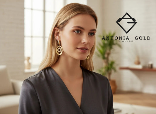 Cercei Antonia Gold din aur cu design oval și pietre strălucitoare purtați de o femeie într-un cadru elegant
