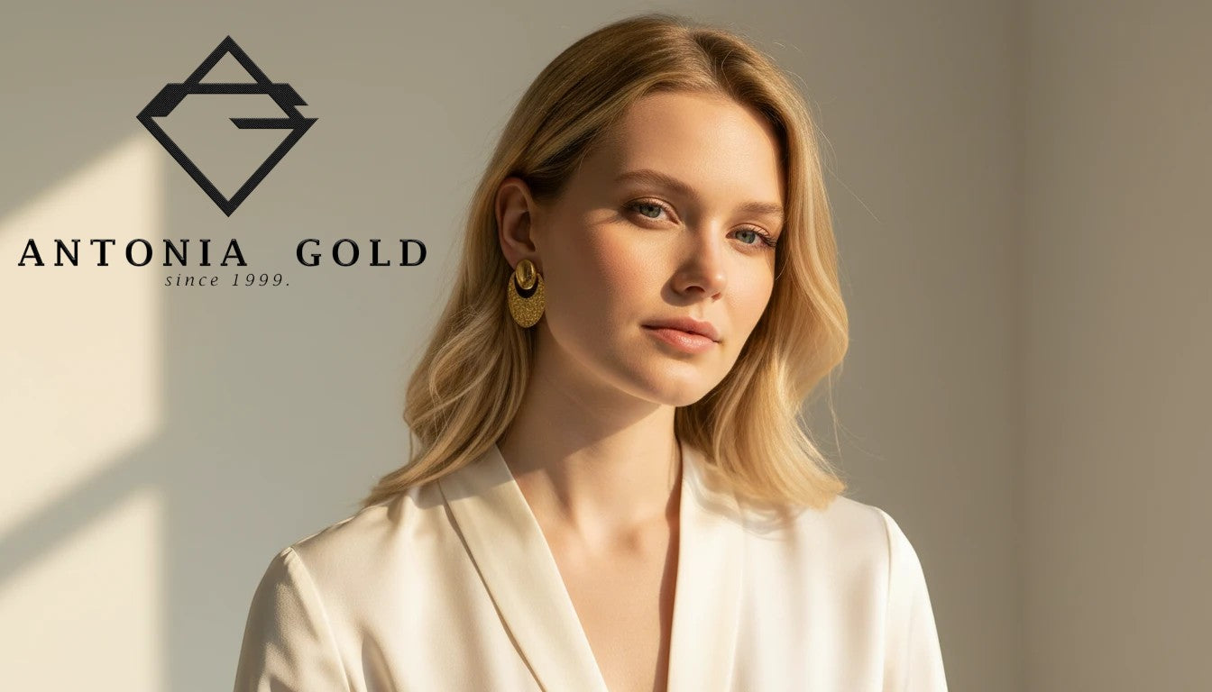 Cercei Antonia Gold din aur galben cu design semilună texturată, purtați de o femeie cu păr blond și bluză albă.