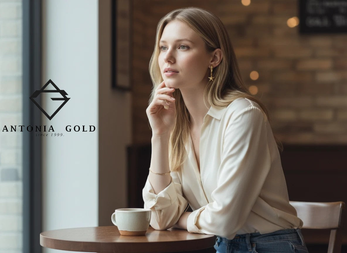 Antonia Gold cercei tip hoop din aur galben cu pandantiv stea purtați de o femeie într-o cafenea
