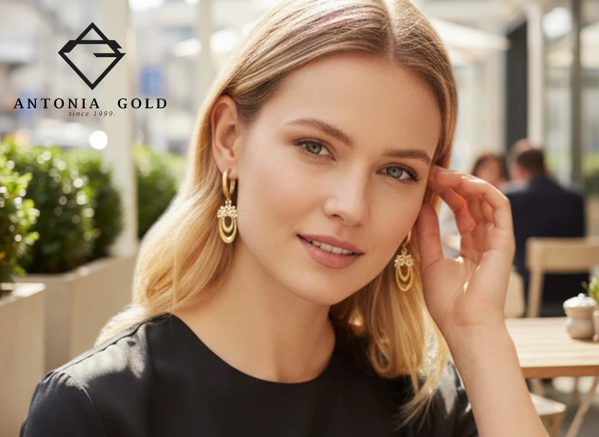 Femeie purtând cercei Antonia Gold din aur cu zirconii, design geometric elegant, într-un cadru urban sofisticat.