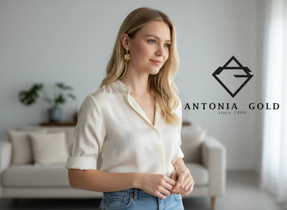 Femeie purtând cercei Antonia Gold tip creole din aur de 14K cu pandantiv trifoi cu patru foi și detalii strălucitoare