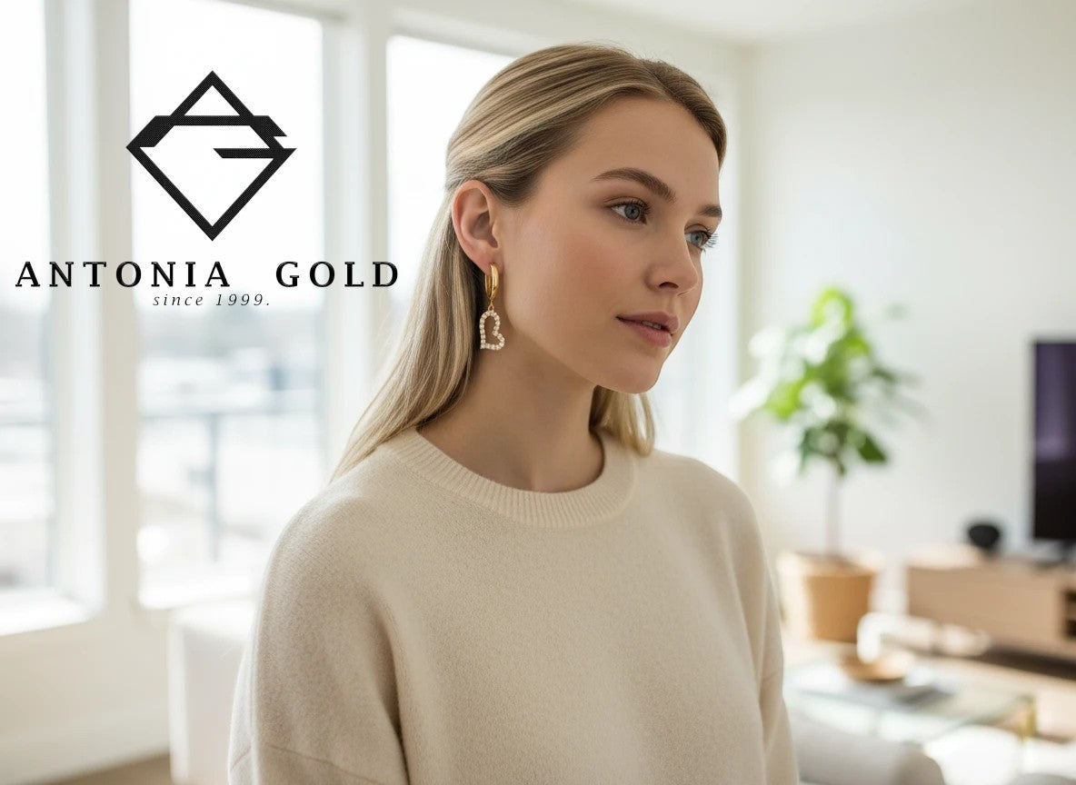 Cercei Antonia Gold tip creole din aur galben cu pandantiv inimă decorat cu pietre albe purtați de o tânără blondă