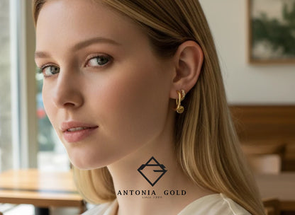 Femeie purtând cercei rotunzi Antonia Gold din aur cu design minimalist și detalii strălucitoare într-un cadru elegant