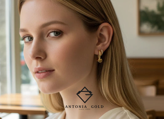 Femeie purtând cercei rotunzi Antonia Gold din aur cu design minimalist și detalii strălucitoare într-un cadru elegant