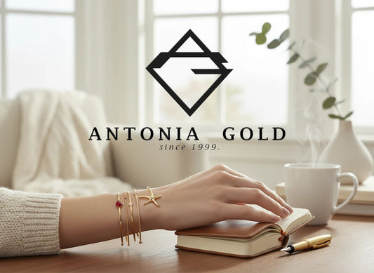 Cercei Antonia Gold în formă de stea de mare din aur galben, purtați ca brățară pe mâna unei femei lângă o carte.